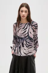 Blusa de manga larga con estampado animal print abstracto en tonos grisáceos y negros. Presenta cuello a la base y cierre con botón en la parte posterior.