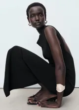 Vestido midi de corte recto y diseño minimalista, confeccionado en tejido elástico. Presenta cuello barco, tirantes anchos, espalda descubierta y una abertura posterior en el bajo.