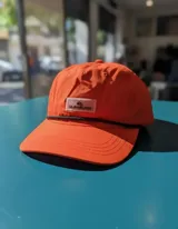 Gorra Quiksilver modelo Flow States de color naranja ladrillo, con visera curva, cordón negro decorativo sobre el ala y parche frontal con el logo de la marca.
