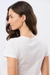 Remera blanca de manga corta y cuello redondo, confeccionada en algodón, con delicado bordado floral localizado en el hombro.