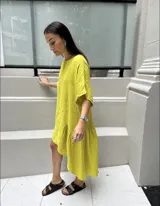 Vestido amarillo de lino con corte asimétrico, más corto adelante que atrás, y volados en el ruedo.