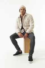 Sobrecamisa de sherpa color crema con cuello camisero, cierre frontal con botones a presión y bolsillo de parche en el pecho. El modelo usa talle M.