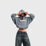 Hoodie oversize color gris, con capucha, bolsillo frontal tipo canguro y el nombre de la marca con una estrella estampados en el pecho en color blanco.