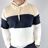 Canguro con capucha color beige, azul marino y blanco, con bolsillo tipo canguro y cordones ajustables.