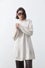 Vestido corto de punto en color beige, con cuello alto acanalado, mangas largas con puños ajustados y diseño holgado.