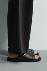 Sandalia monocolor negra con tiras cruzadas en el empeine, detalle de hebilla metálica rectangular y plantilla con horma anatómica.