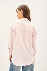 Camisa de algodón color rosado con cuello mao, cierre frontal con botones de nácar y bordado artesanal multicolor en el pecho. Presenta un cordón decorativo en el cuello con borlas.