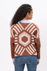 Buzo tejido de punto con diseño geométrico tipo mandala en tonos marrón, beige y blanco. Presenta cuello redondo y puños en color celeste pastel, con corte holgado y mangas largas.