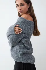Sweater de punto tricot con diseño off-shoulder, de calce relajado y mangas largas. Presenta una textura suave y flexible con cuello amplio que cae sobre los hombros.