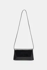 Bolso tipo bandolera y sobre color negro con acabado brillante y efecto charol. Cuenta con estructura rígida rectangular, solapa frontal con cierre de botón imantado y correa fina para el hombro.