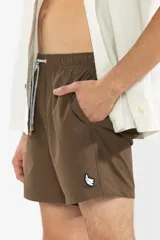 Short de baño marrón con bordado de enredadera en la pierna izquierda, cintura elástica con cordón ajustable, bolsillos laterales y bolsillo trasero con cierre.