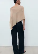 Poncho de tejido ligero y traslúcido en color beige, con diseño asimétrico y corte holgado.