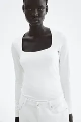Remera blanca de punto suave, entallada, con escote cuadrado y mangas largas.
