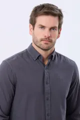 Camisa de manga larga con cuello abotonado y cierre frontal de botones. Presenta un diseño liso en color azul oscuro con un pequeño logo bordado en el pecho.