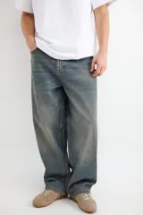 Jean de corte holgado y tiro medio, confeccionado en denim de algodón con lavado oscuro y efecto desgastado vintage. Presenta pierna ancha y diseño de cinco bolsillos.