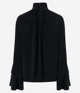 Blusa Cortelle estilo bata, color negro, con cuello alto fruncido, cierre posterior y mangas largas amplias tipo campana con volados en capas.