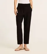 Pantalón de vestir negro, estilo carrot (holgado en cadera y ajustado en tobillo), de cintura alta con trabillas y cierre tradicional. Presenta recortes verticales con costura aparente en el frente.