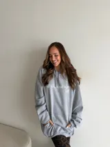 Hoodie canguro gris melange, de corte oversize, con capucha ajustable mediante cordón, bolsillo tipo canguro y estampado frontal con la frase "All you need is love a self".