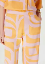 Pantalón de corte recto y largo cropped, con estampado geométrico abstracto en tonos naranja y rosado. Presenta cintura elastizada para mayor comodidad.