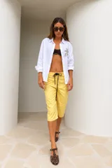 Bermuda de calce relajado y pierna amplia, color amarillo, con largo por debajo de la rodilla y cordón ajustable negro en la cintura.