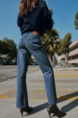 Jeans de tiro alto con diseño de cinco bolsillos, pernera recta y corte largo. Presenta cierre frontal con cremallera y botón metálico.