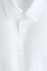 Camisa H&M de corte relajado, confeccionada en tejido liviano de mezcla de lino y algodón color blanco. Presenta cuello inglés, cierre frontal de botones, manga larga con puños ajustables y bolsillo aplicado en el pecho.