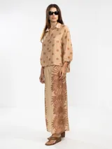 Pantalón palazzo color beige con estampado de girasoles marrones en el ruedo.