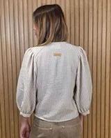 Camisa de cuello redondo y manga larga abullonada, con diseño a rayas en tonos rosado y blanco.