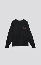 Sweater de punto negro con textura suave, cuello redondo y diseño oversize. Presenta un bordado frontal con la frase 'art SUPPORT' en letras rojas y blancas, y un pequeño detalle de tijeras bordado en la nuca.