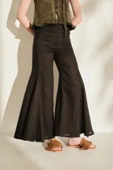 Pantalón negro de lino de tiro alto, con diseño ajustado en las caderas y perneras amplias y acampanadas con paneles insertados que generan mucho vuelo en el bajo.