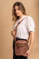 Morral bandolera color marrón de tela impermeable con correa ajustable. Tiene dos bolsillos frontales con cierre y dos bolsillos internos.