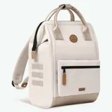 Mochila Cabaia modelo Adventurer Alger, color beige con detalles dorados. Cuenta con un bolsillo frontal con cierre, asas superiores y tirantes acolchados.