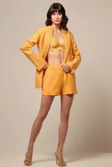 Blazer de corte sastre en color naranja, con solapas clásicas y manga larga. La prenda presenta un acabado texturizado con incrustaciones de strass en toda su superficie, aportando un brillo sutil y sofisticado.