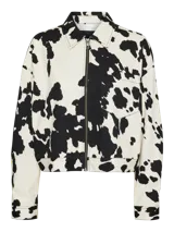Chaqueta corta con cuello clásico, cierre frontal con cremallera, puños abotonados y estampado de manchas de vaca en blanco y negro.
