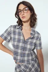 Camisa de manga corta con cuello, entallada al cuerpo, confeccionada en tejido a cuadros azul, blanco y marrón.