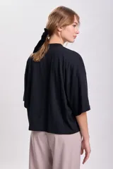 Remera negra de corte holgado, con cuello alto y mangas 3/4.