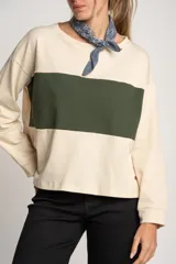 Sweater color crema con una franja horizontal verde en el pecho, de corte oversize y mangas largas.