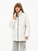 Campera puffer color blanco hueso, con cuello alto, cierre frontal con cremallera y bolsillos laterales con cierre.
