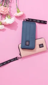 Billetera larga con cierre perimetral, confeccionada en nylon capitoneado color verde petróleo. Cuenta con correa de mano desmontable con logo estampado y parche frontal con marca LNS.