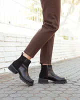 Botinetas de cuero negro con paneles laterales de gamuza al tono. Presentan una suela track robusta con taco cuadrado y cierre lateral para facilitar el calce.