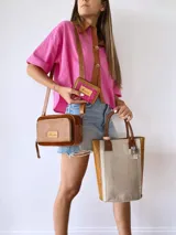 Bolso matero de cuero color beige con textura de reptil y detalles en cuero marrón con textura de cocodrilo. Incluye manijas cortas de cuero marrón y dije de cruz plateada.