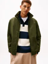 Campera Tommy Hilfiger de color verde militar, con cuello alto, cierre frontal de cremallera y bolsillos laterales. Confeccionada en poliamida, presenta un diseño clásico y versátil con el logo de la marca bordado discretamente en el pecho.