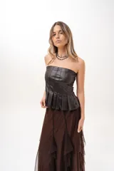 Top strapless de cuero sintético color marrón, con diseño de pliegues verticales tipo corsé y corte péplum en la parte inferior.