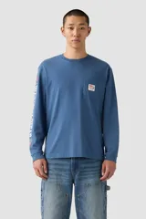 Remera de manga larga color azul, con cuello redondo, bolsillo en el pecho con etiqueta de la marca y estampado vertical en la manga izquierda.