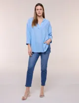 Blusa de silueta holgada a rayas verdes y blancas, confeccionada en tela liviana con textura arrugada. Presenta cuello en V profundo con botones frontales, mangas 3/4 de hombro caído y ruedo asimétrico con aberturas laterales.