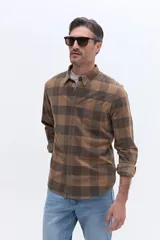 Camisa de manga larga confeccionada en viyela de algodón con diseño a cuadros en tonos verde oscuro. Presenta cuello clásico, cierre frontal con botones y bolsillo aplicado en el pecho.