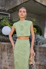 Top corto de color verde lima con diseño calado de motivos circulares y abanicos. Presenta cuello a la caja, sin mangas y un corte recto tipo crop top.