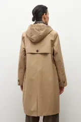 Trench impermeable color beige con cuello camisero en contraste de color marrón oscuro. Presenta cierre frontal con botones, bolsillos delanteros con solapa y mangas largas.