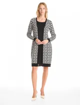 Vestido midi de tejido de punto con diseño integrado que simula un conjunto de vestido negro liso con un cárdigan largo estampado de eslabones geométricos en blanco y negro. Presenta escote redondo y mangas largas.