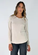Remera de manga larga en color beige, confeccionada en tejido de punto suave, con detalle de puntilla decorativa en el escote redondo.